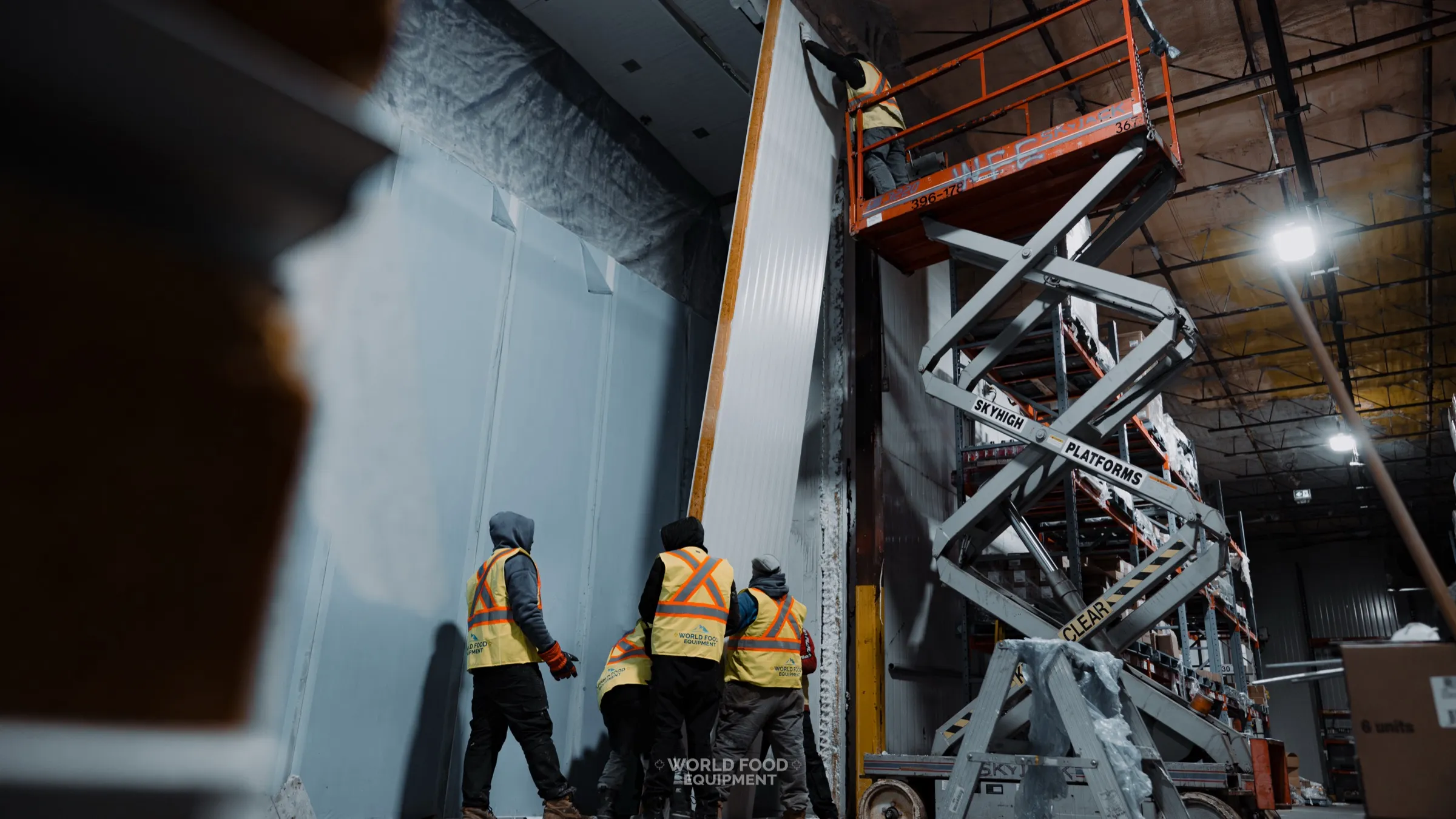 CJR Grocers 140 ft freezer wall rebuild video poster, WFE crew setting new insulated panels with scissor lift while the grocery facility kept operating