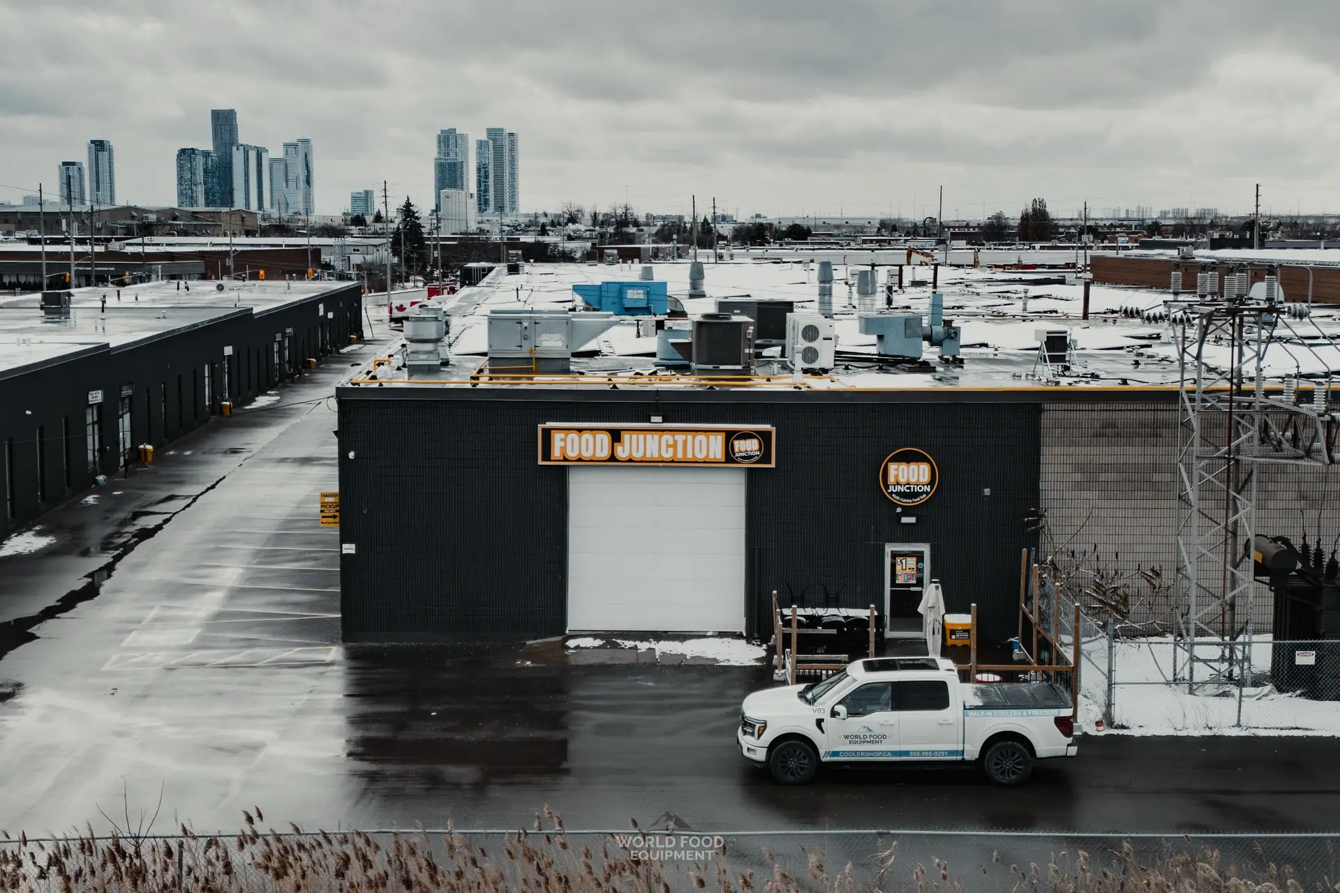 Food Junction Toronto, exterior view of the WFE customer building with a World Food Equipment service truck out front and the Toronto downtown skyline in the distance, snowy winter day, commercial walk-in cooler installation by World Food Equipment