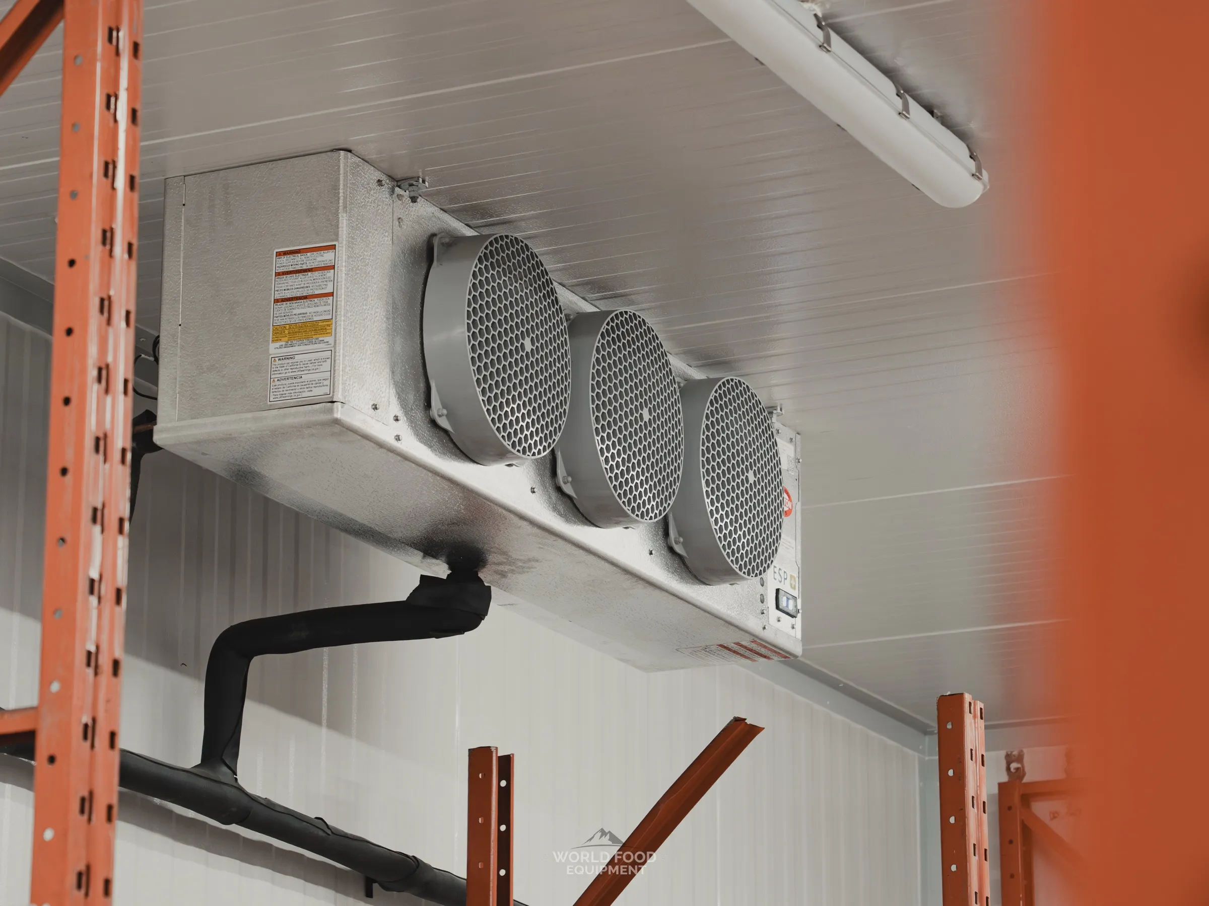 Finished 10' × 20' walk-in freezer at the Stainless Steel project with five-fan ceiling-mounted evaporator, custom-designed shelving stocked with product, and reinforced concrete floor finished in epoxy.