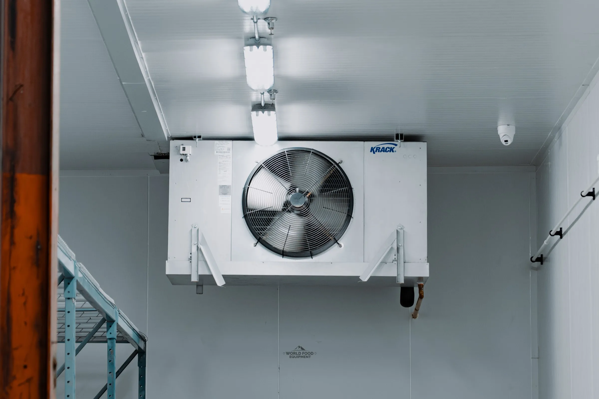 KRACK single-fan evaporator in a finished walk-in cooler at the Food Junction install in Mississauga, Ontario, with the insulated condensate drain line dropping from the pan to the wall, World Food Equipment