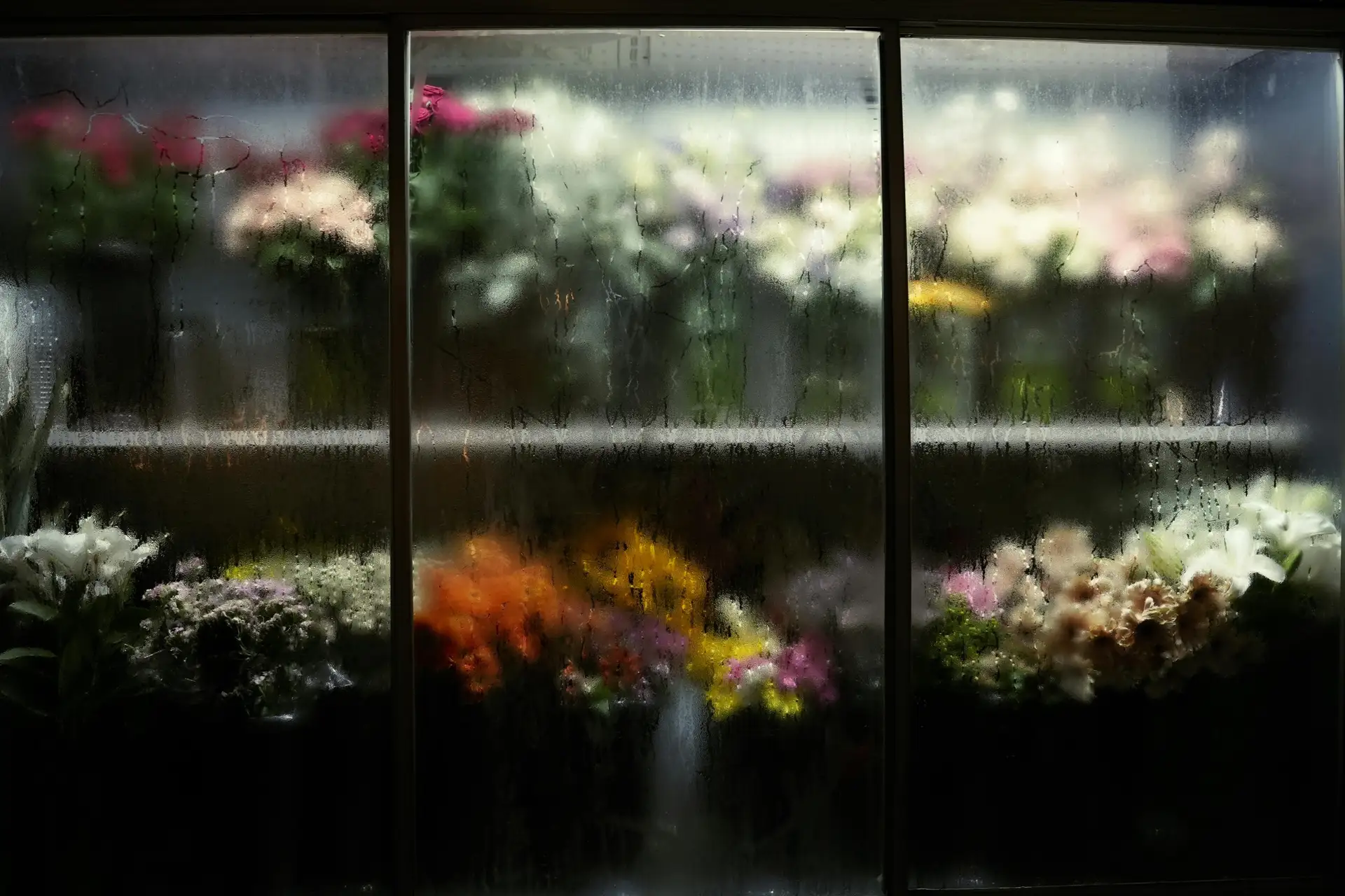 Florist walk-in cooler with condensation on glass doors, fresh-cut flowers visible behind glass at high humidity