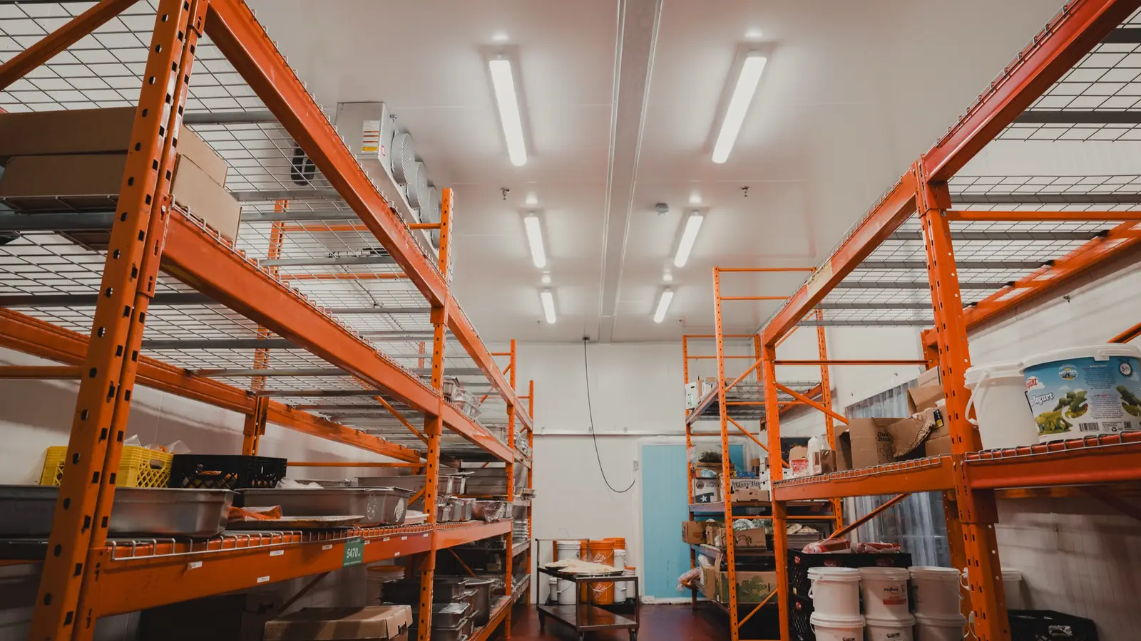 Inside a World Food Equipment walk-in in Ontario showing the ceiling evaporator, insulated door with strip curtain, and pallet racking