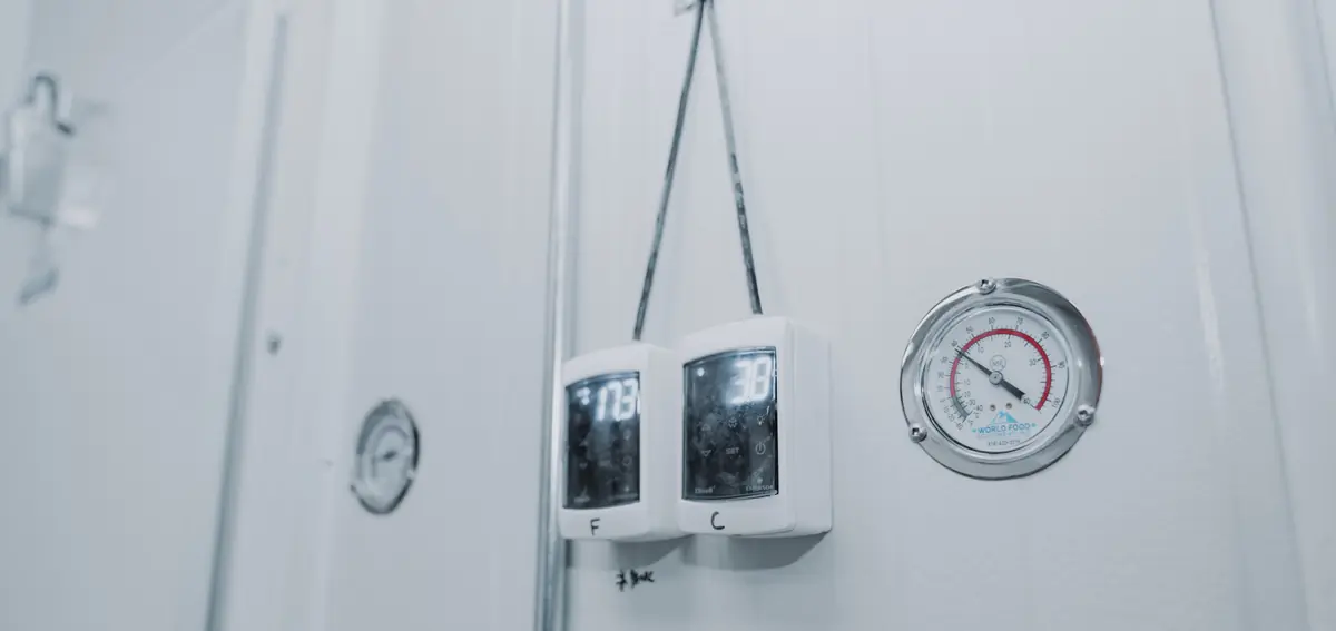 Two digital thermometers reading in Fahrenheit and Celsius hung beside a WFE dial thermometer on the door of a Toronto walk-in cooler