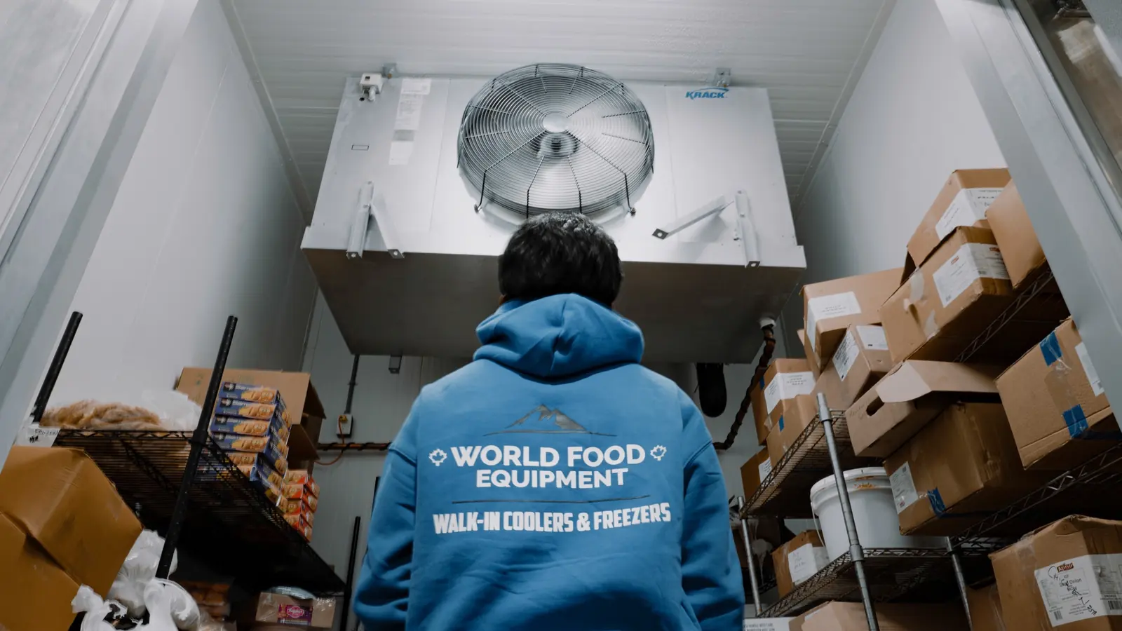 World Food Equipment crew member checking the evaporator fan inside a stocked walk-in cooler in Toronto, Ontario