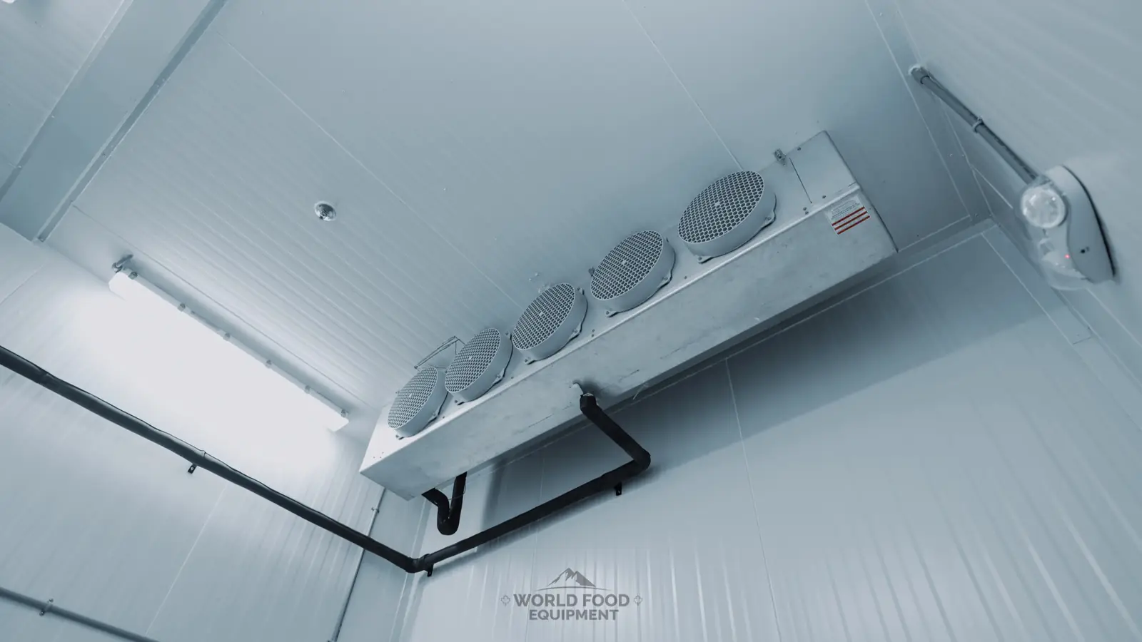Multi-fan ceiling evaporator with insulated refrigerant lines inside a clean walk-in freezer built by World Food Equipment in Ontario