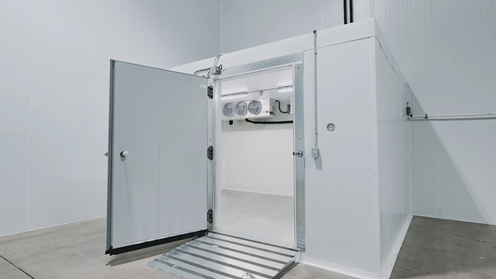 Open insulated walk-in swing door with three cam-lift hinges, an aluminum frame, latch and inside release, and an aluminum threshold ramp, Pacer Air Freight cold room install by World Food Equipment in Ontario