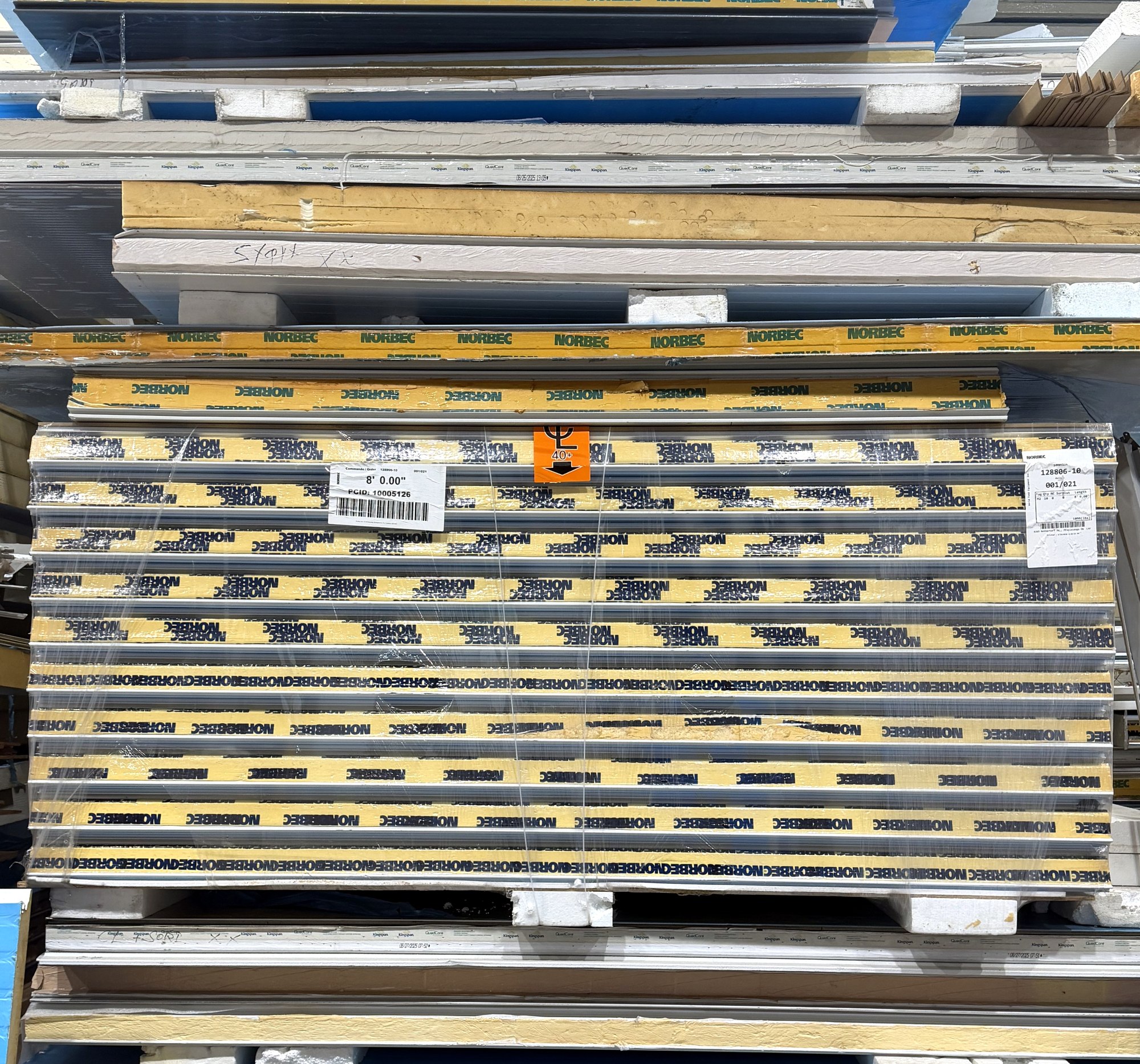 Shrink-wrapped pallet of Norbec insulated walk-in panels labelled 8 feet 0 inches at the World Food Equipment warehouse in Mississauga, with Kingspan QuadCore panel bundles stacked above and below